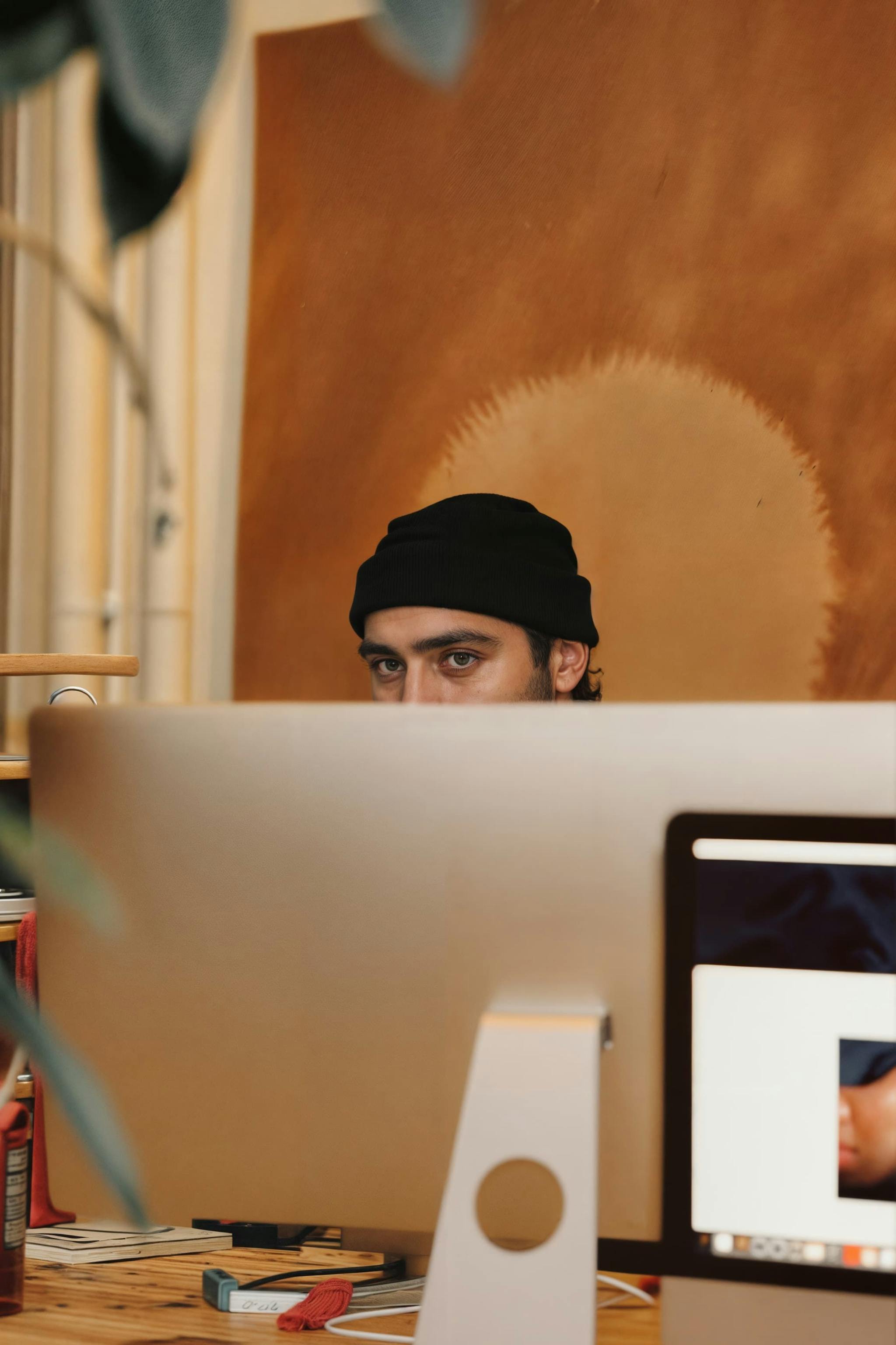 A man is peering over a computer